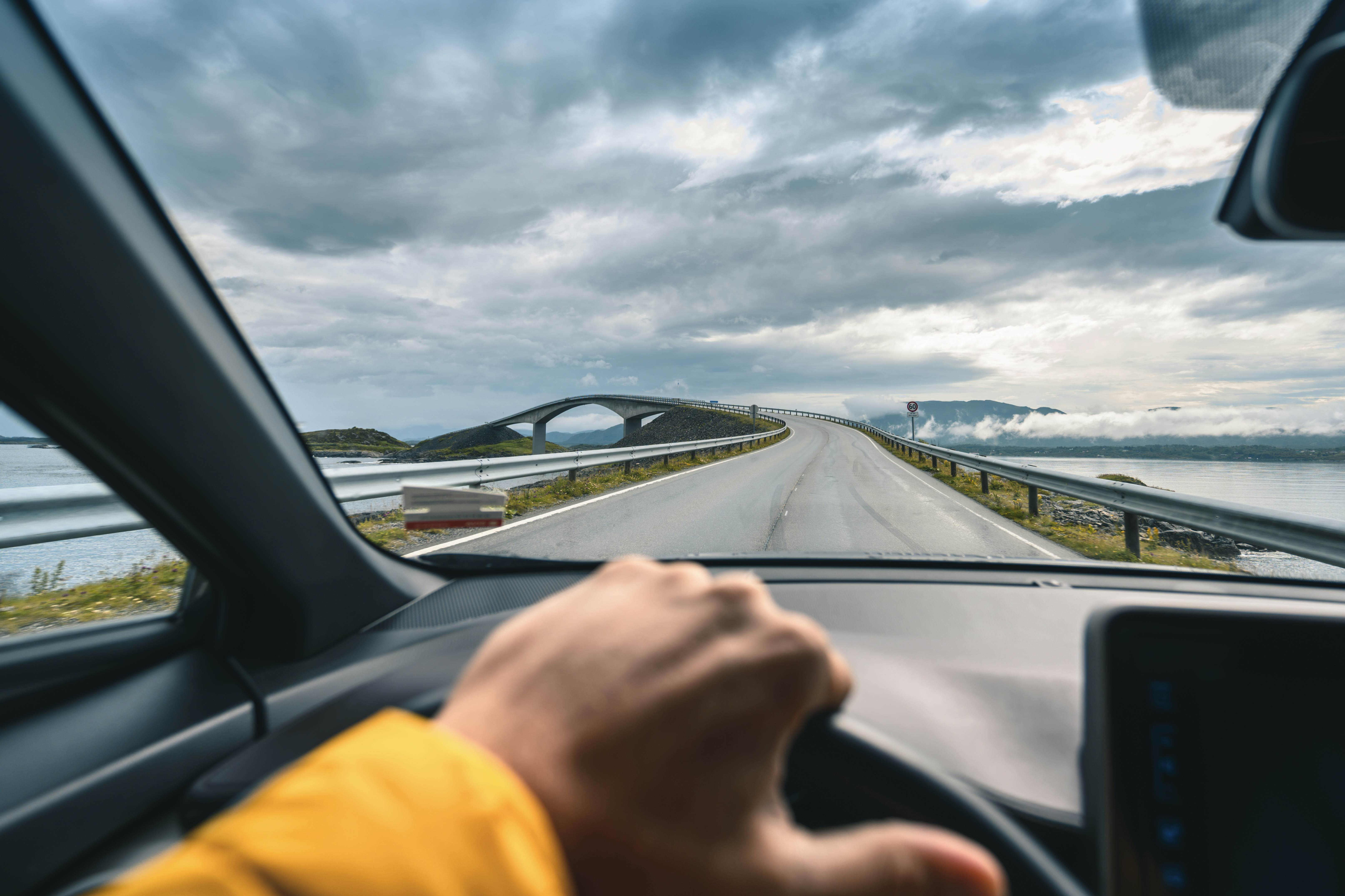 Tourist driving on the Atlantic Road with the famous Storseisundet bridge in the background